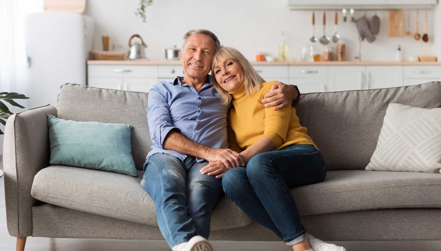 A smiling couple sitting on a sofa.